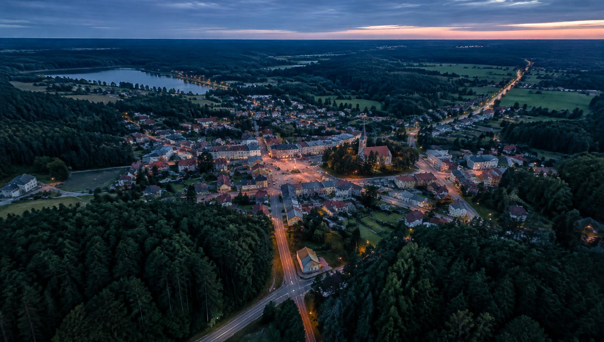 Miasto otoczone lasami o zmierzchu, widok z lotu ptaka
